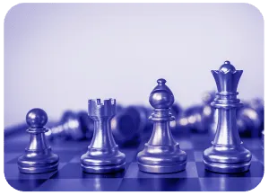 Four standing chess pieces on a board with toppled pieces behind them