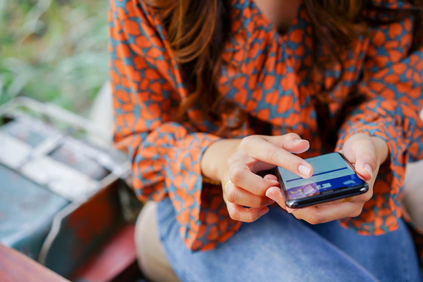 A Woman Holding a Smartphone and Browsing on Facebook