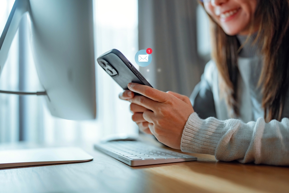 A woman looking down at her phone smiling at an unread email