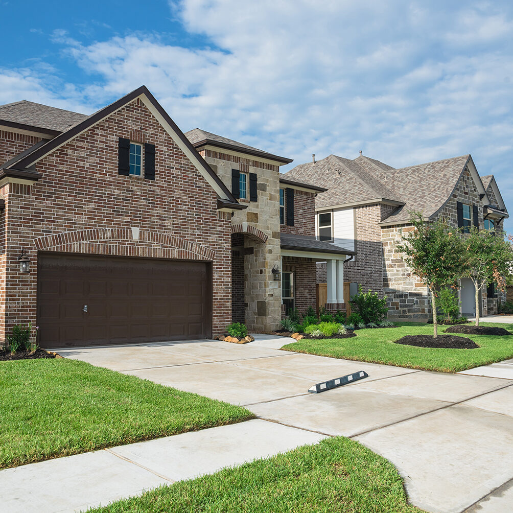 Suburban American neighborhood street with row of brand new two story residential houses in Humble, Texas, US. Newly constructed, freshly built modern home with landscaped yard.